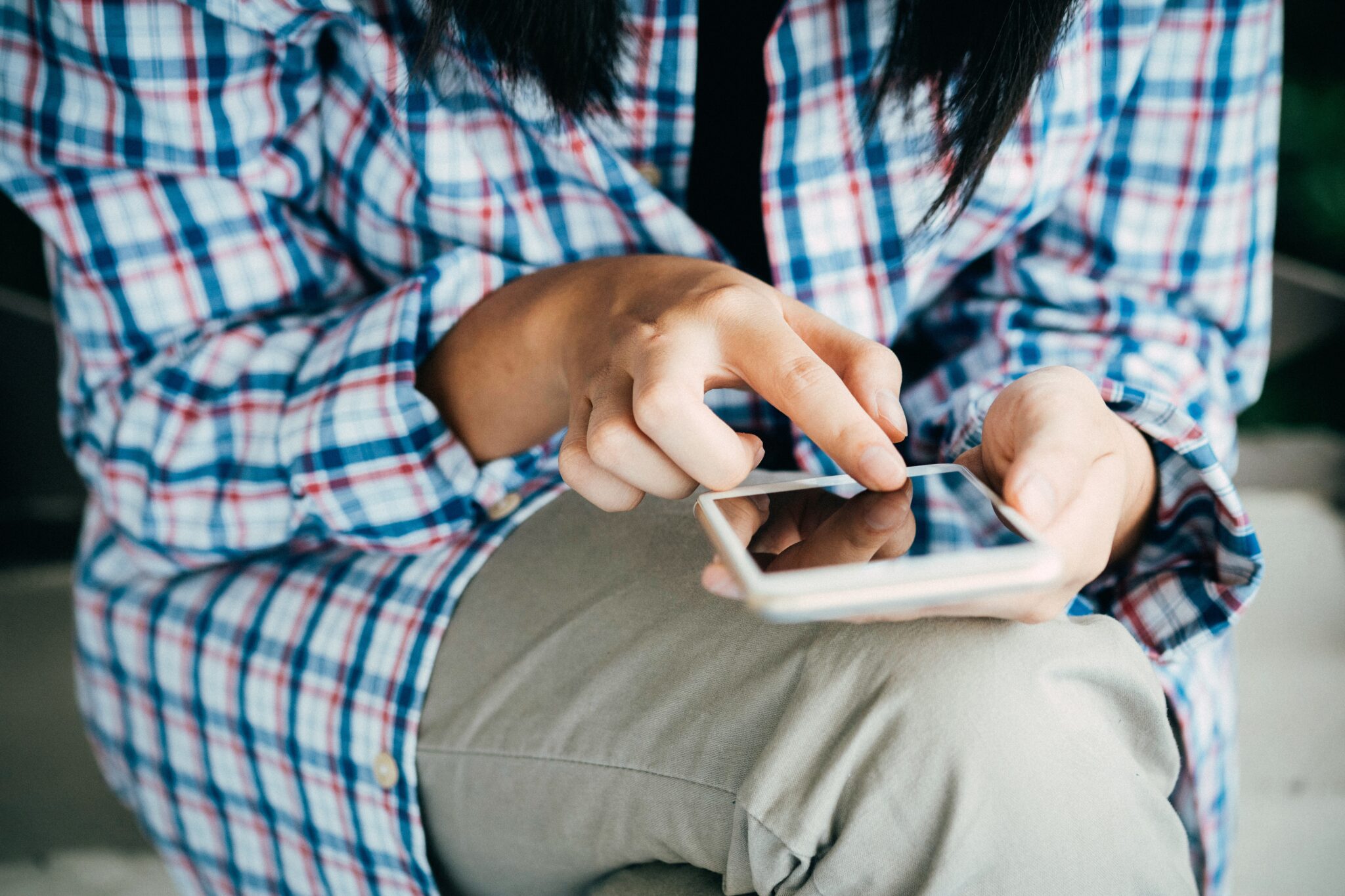 Women sits crossed legged while scrolling through her mobile phone