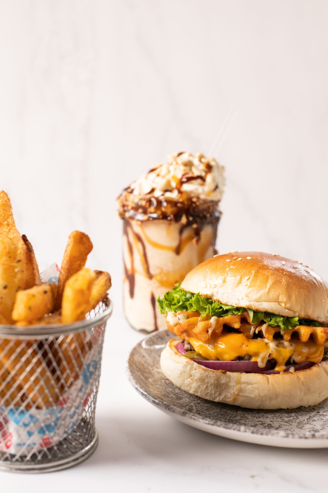 burger, fries and milkshake on plain backdrop